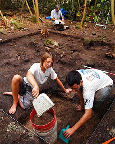 Anthropology Professor James Bayman records notes in background as UH undergraduate student Jacqueline Fee and University of Guam student Andrew Viloudaki conduct archaeological excavation work in Guam in 2008.