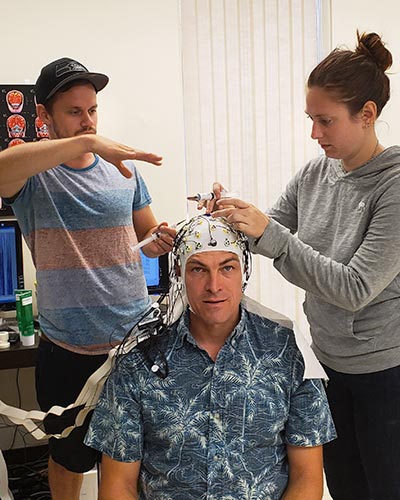 Brain and Behavior Lab members David Thinnes and Tien Austin affix an electroencephalogram (EEG) cap on Jonas Vibell’s head to detect the electrical activity of the brain.