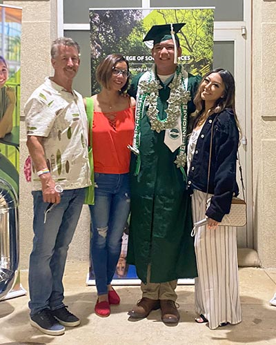 Justin Nguyen, in his UH Mānoa cap and gown, with well-wishers at Commencement in December 2021.