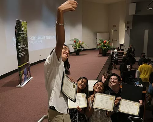 Student taking selfie of other students holding their certificates.